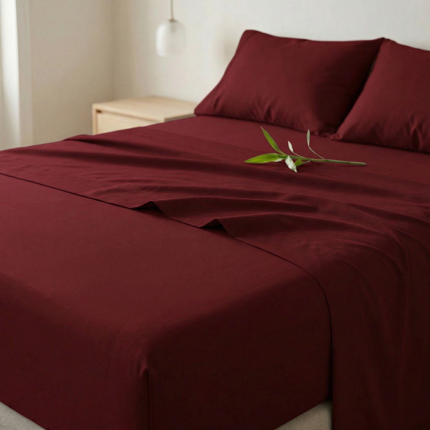 Decolure Burgundy bamboo sheet set styled on bed in bedroom setting, showing soft bamboo fabric texture and elegant drape