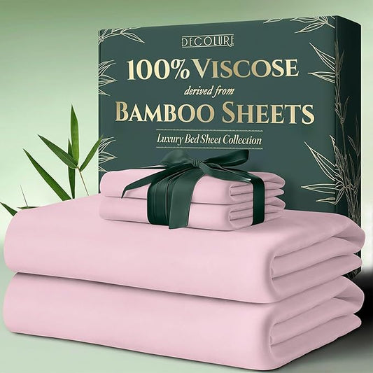 Light pink bamboo viscose bed sheets neatly folded with green ribbon and dark green packaging box with gold text.