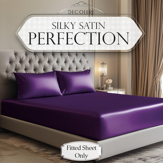 Deep purple satin fitted sheet on bed with matching pillowcases in elegant bedroom setting.
