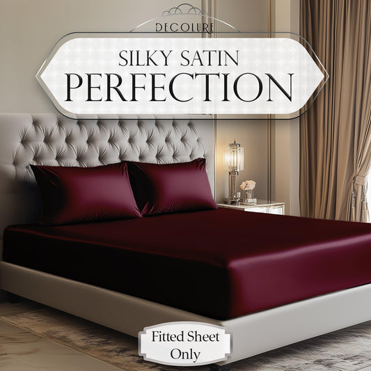 Deep rosewood satin fitted sheet on beige upholstered bed with matching pillowcases in elegant bedroom.