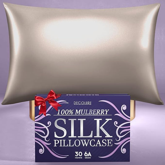Champagne-colored silk pillowcase with smooth sheen above rectangular purple box with red ribbon and white lettering.