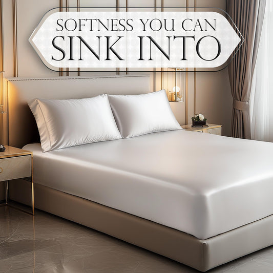 White satin fitted sheet on bed with matching pillows in modern bedroom setting.