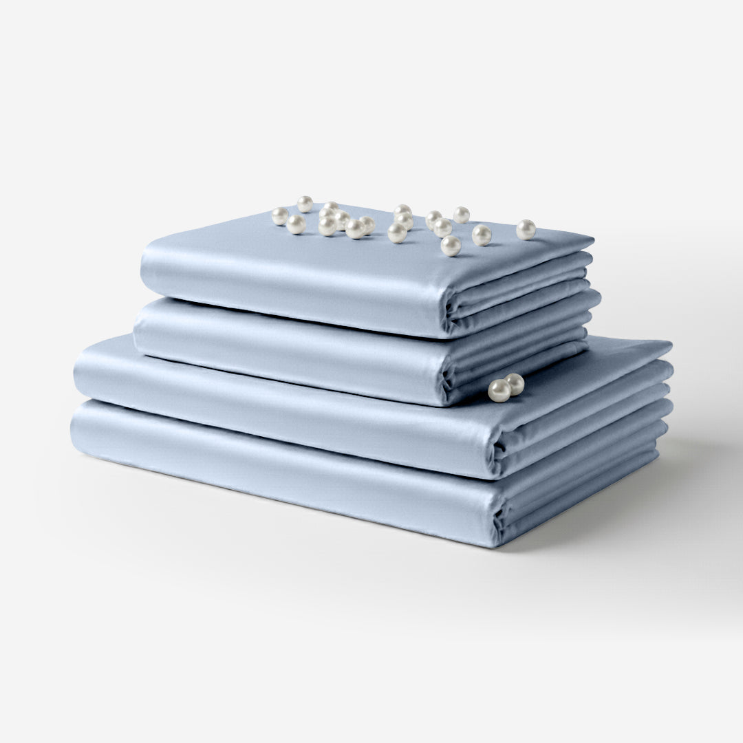 Neatly folded baby blue satin bed sheets stacked with small white flowers on top.