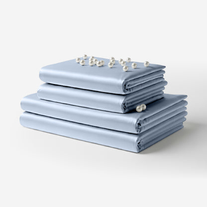 Neatly folded baby blue satin bed sheets stacked with small white flowers on top.