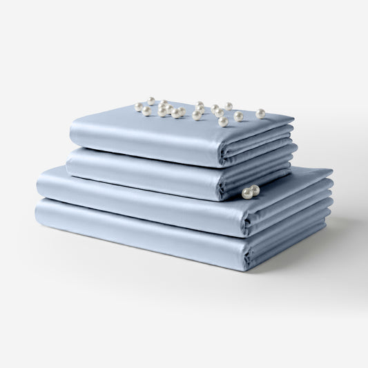 Neatly folded baby blue satin bed sheets stacked with small white flowers on top.