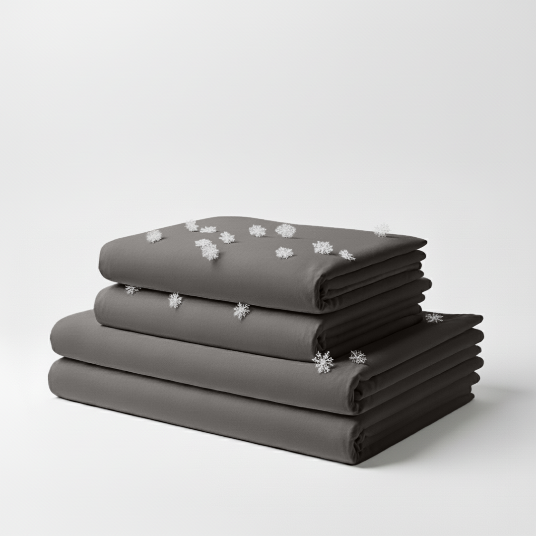 Stacked cool grey folded cooling sheet set with small white snowflake icons scattered on top.
