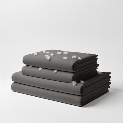 Stacked cool grey folded cooling sheet set with small white snowflake icons scattered on top.