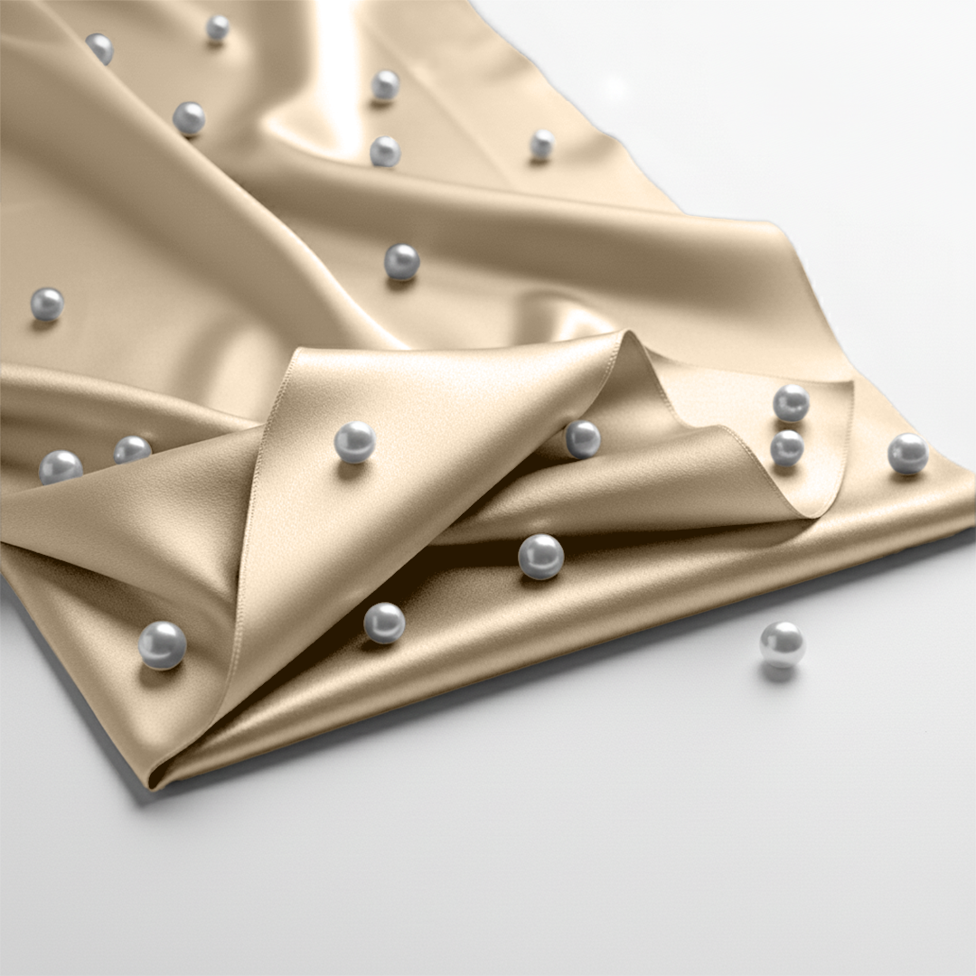 Ivory satin fitted sheet with smooth, glossy texture adorned with scattered silver spheres.