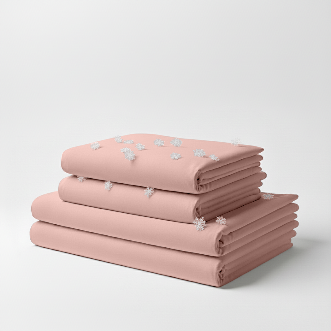 Light pink folded cooling sheet set with subtle white floral embroidery on top sheet.