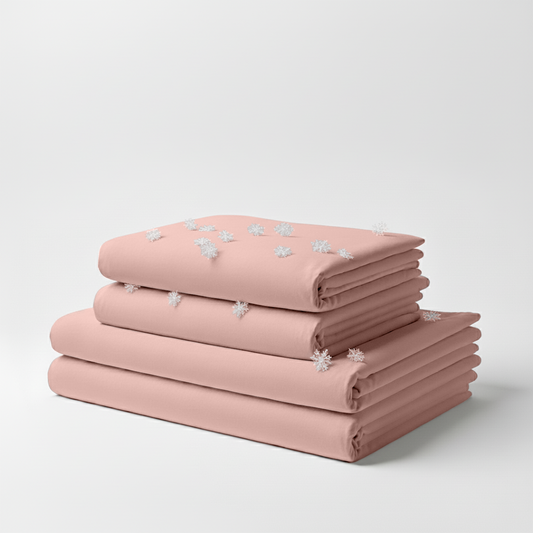 Light pink folded cooling sheet set with subtle white floral embroidery on top sheet.