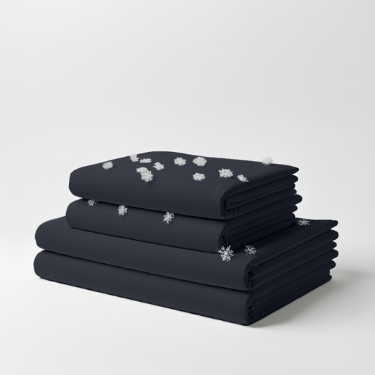 Stack of neatly folded midnight black cooling bed sheets with snowflake icons indicating cooling effect.