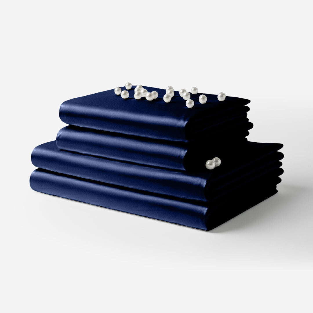 Navy blue satin sheet set neatly folded with smooth, glossy fabric finish.