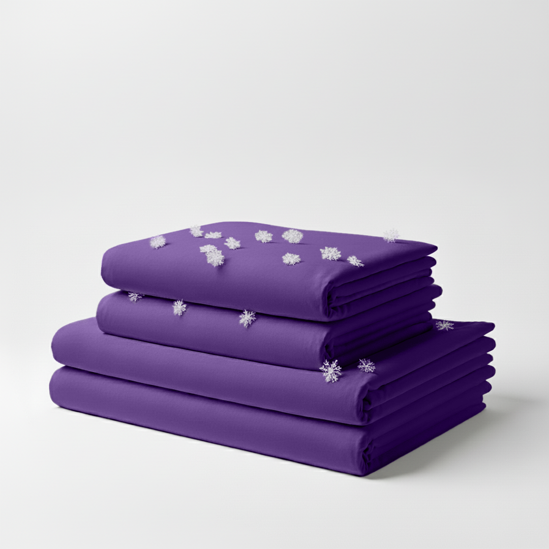Stack of folded regal purple cooling bed sheets with small white snowflake patterns on top.