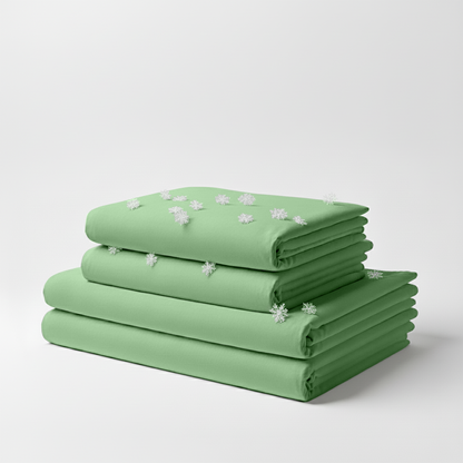 Sage green cooling sheet set neatly folded with small white embroidered flowers on top sheet.