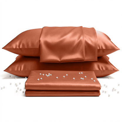 Set of burnet orange satin pillows and a folded sheet with pearls on a white background