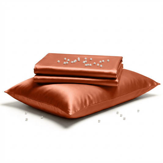 Burnt orange-colored satin sheet set with a pillow on a white background