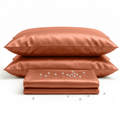Set of burnet orange-colored satin pillows and a sheet on a white background