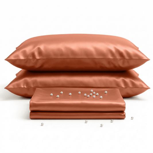 Set of burnet orange-colored satin pillows and a sheet on a white background