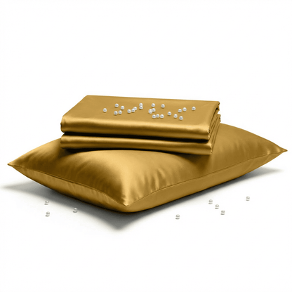Gold satin sheet set with a pillow on a white background