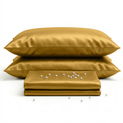 Gold satin pillowcases with a small folded gold sheet on a white background