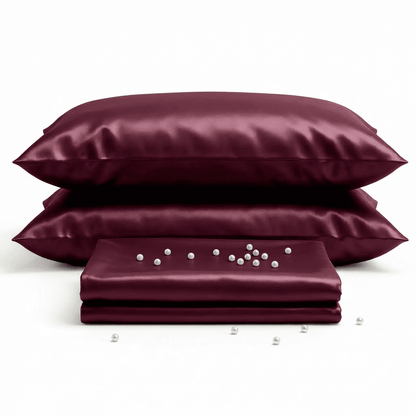 Burgundy satin pillowcases and a folded sheet on a white background