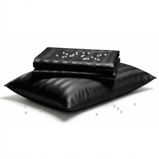 Black satin pillow and blanket set on a white background