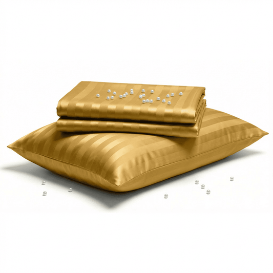 Gold satin pillow and folded sheet on a white background
