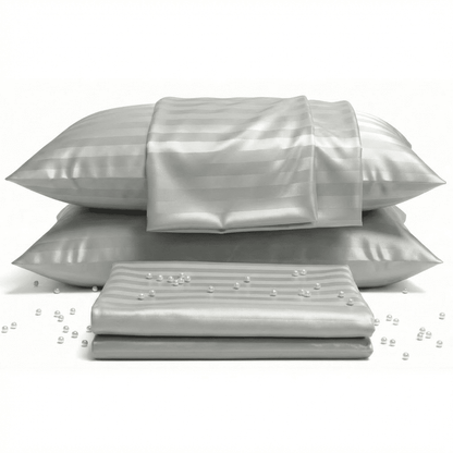 Set of silver satin pillows and a sheet on a white background