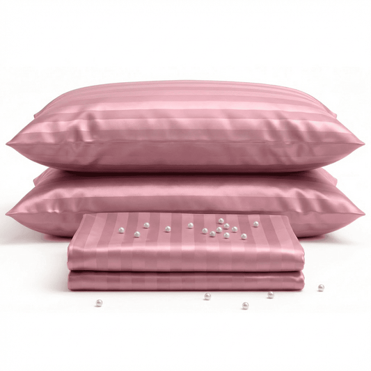Pink satin pillowcases and sheet set on a white background