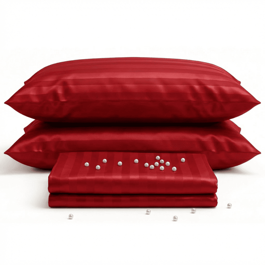 Red satin pillowcases and a folded red satin sheet on a white background