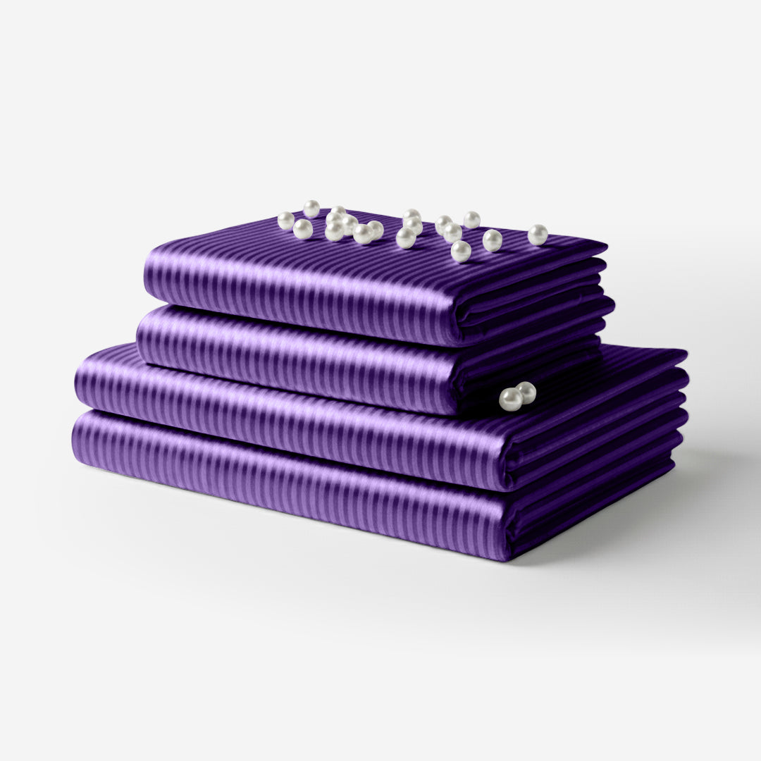 Folded purple satin sheet set with subtle horizontal stripes and a smooth, shiny finish.