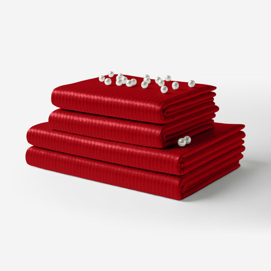 Stacked red satin sheets with subtle vertical stripes and a smooth, glossy finish.