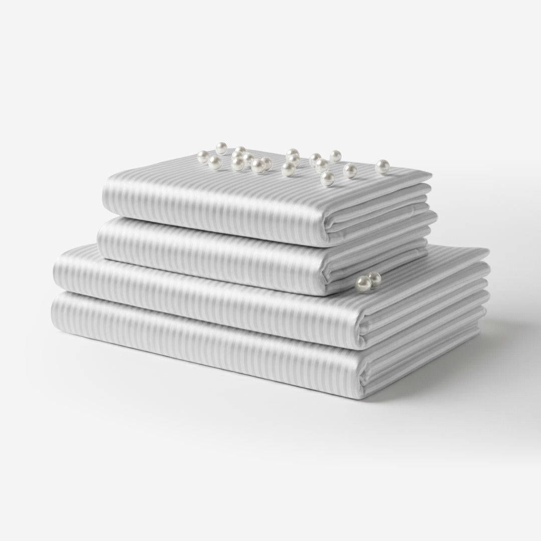 Folded white satin sheet set with subtle vertical stripes and smooth texture, stacked neatly.