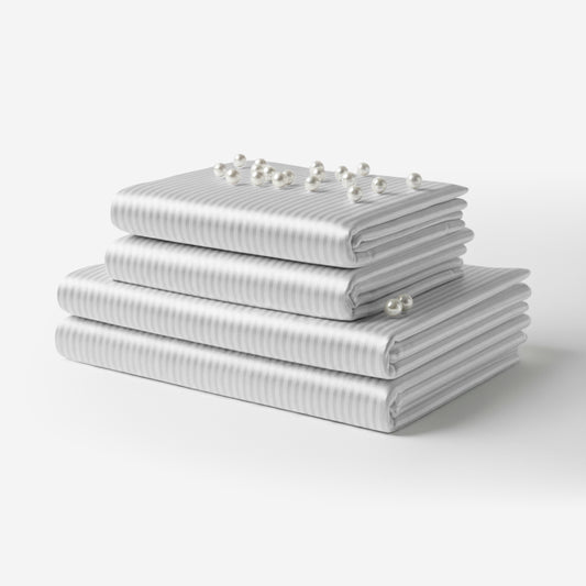 Folded white satin sheet set with subtle vertical stripes and smooth texture, stacked neatly.