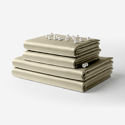 Folded taupe satin sheet set stacked with pearl and crystal accents on top.