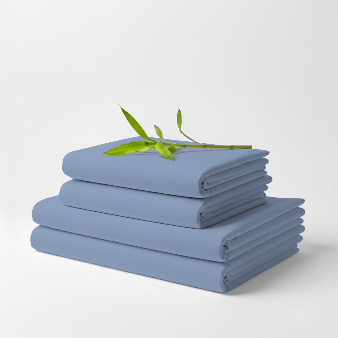Light blue bamboo sheet set folded in three stacked layers with green leaf on top.