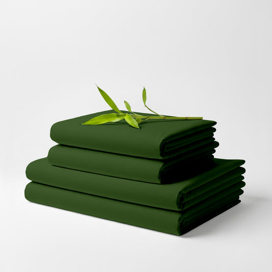 Stack of neatly folded olive green bamboo bed sheets with a small green leafy branch on top.