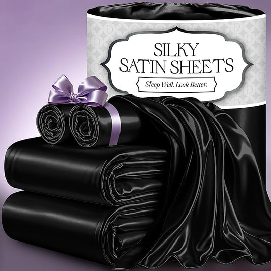 Black satin sheet set with smooth, shiny finish, including folded and draped sheets, rolled pillowcase tied with purple.