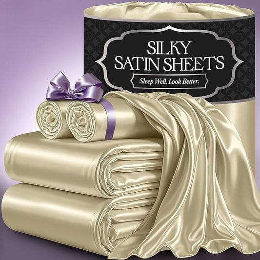 Champagne satin sheet set with smooth, shiny fabric, includes folded and rolled sheets with purple ribbon on light purple.