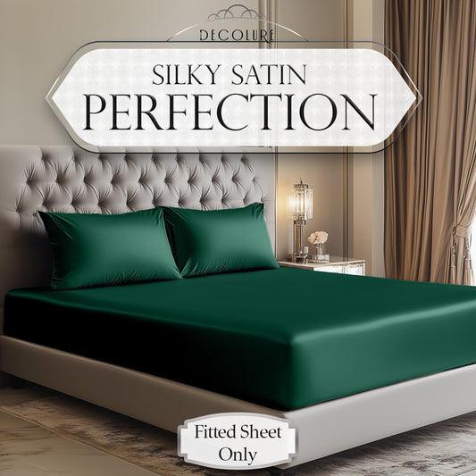 Dark green satin fitted sheet on a modern tufted bed with matching pillowcases.
