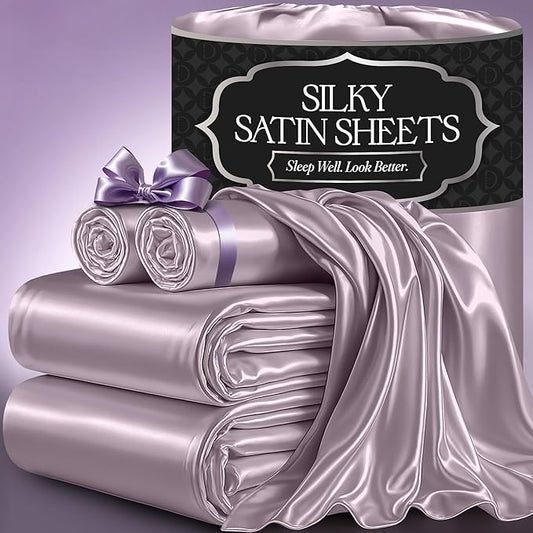 Lavender satin sheet set with smooth, shiny fabric stacked beside matching pillowcases and fitted sheet.