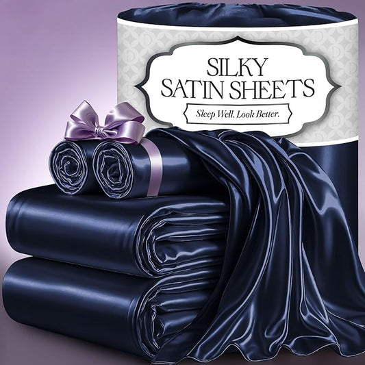 Navy blue silky satin sheet set with pillowcases, folded and rolled with a lavender ribbon on purple background.