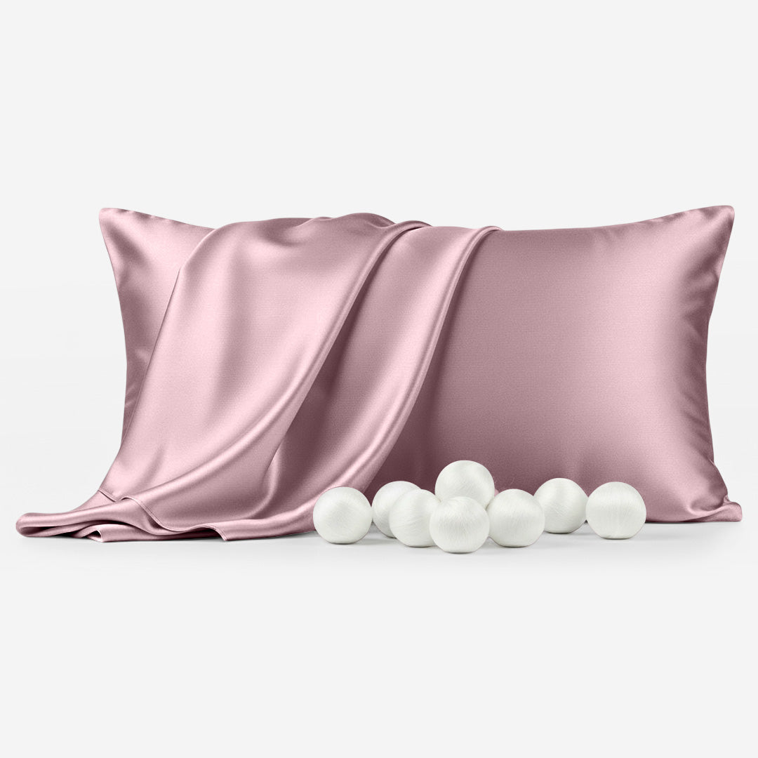 Coral silk pillowcase with smooth, shiny texture and six white decorative balls in front.