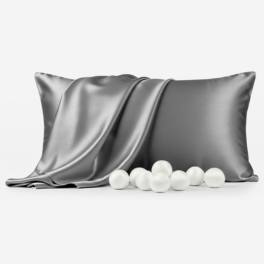 Grey silk pillowcase with smooth, shiny texture next to scattered white balls.