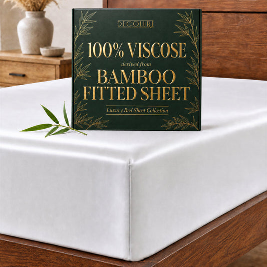 Dark green Decolure fitted sheet box on a white fitted sheet over a wooden bed