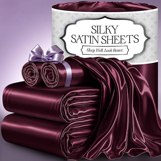 Deep rosewood satin sheets stacked with smooth, glossy texture and tied pillowcases with lavender ribbons.